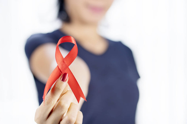 Closeup of woman hand holding a world AIDS day awareness ribbon in the studio - 写真・画像