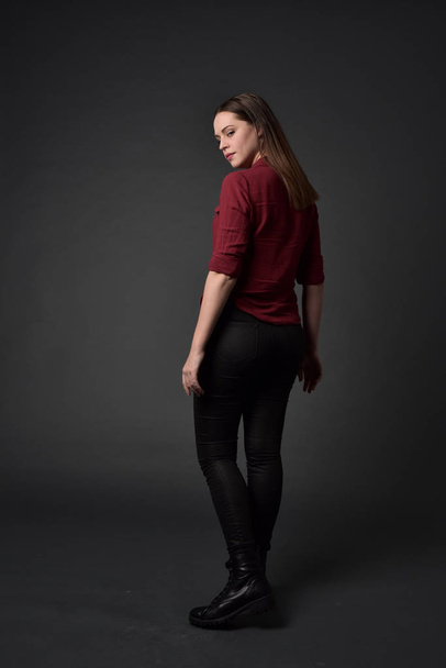 Pełna długość Portret brunetka dziewczyna ubrana w czerwoną koszulę i Spodnie skórzane. pozie stojącej, na studio szary tło. - Zdjęcie, obraz