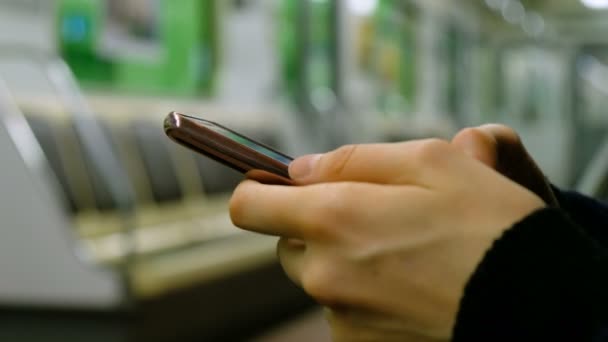 Girl is using a smartphone in a subway close-up - Footage, Video
