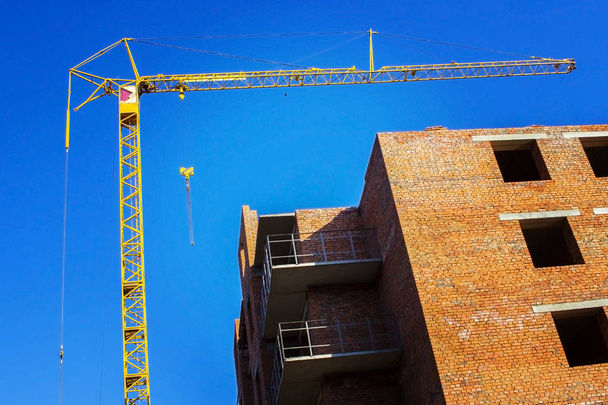 Building crane and building under construction against blue sky - Photo, Image