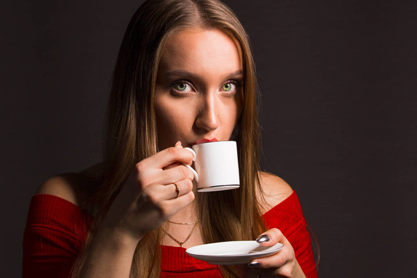 The blonde with long hair and green eyes drinks hot coffee. The concept of emotion concentration and thinking. - Fotoğraf, Görsel