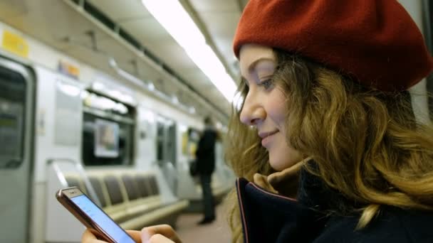 Mooie jonge vrouw maakt gebruik van een smartphone in de metro close-up, een meisje wordt afgedrukt op een bericht in de telefoon - Video