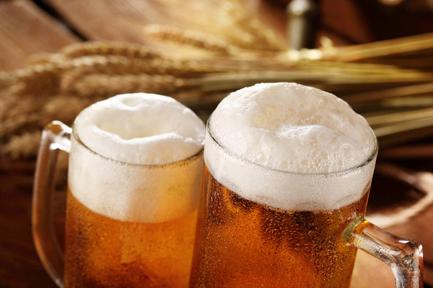 2 杯のビール。Bakcground の小麦と大麦とバレルのスパイク。クローズ アップの選択と集中 - 写真・画像