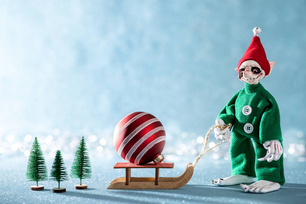 Roztomilý veselý Santas Helper Elf tahání Santovy saně s vánoční Bauble.North pólu vánoční Scene. Santas Workshop. Skřítek při práci.  - Fotografie, Obrázek
