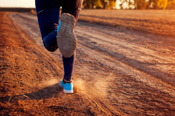 Женщина бежит на осеннем поле на закате. Понятие здорового образа жизни. Активные спортивные люди. Закрыть ноги
 - Фото, изображение