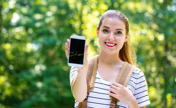 Young woman holding out a smartphone - Photo, Image
