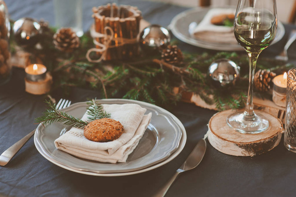 Festive Christmas and New Year table setting in scandinavian style with rustic handmade details in natural and white tones. Dining place decorated with pine cones, branches and candles - Foto, Bild