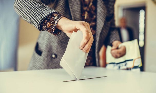 Farbbild einer Person, die während der Wahlen in einem Wahllokal einen Stimmzettel abgibt. - Foto, Bild