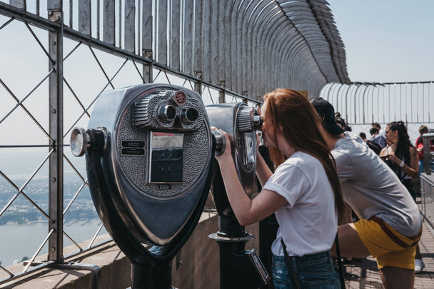 Nueva York, EE.UU. - 29 de mayo de 2018: Visitantes que usan prismáticos en la plataforma de observación del Empire State Building, Nueva York. Nueva York es una de las ciudades más visitadas del mundo
. - Foto, Imagen