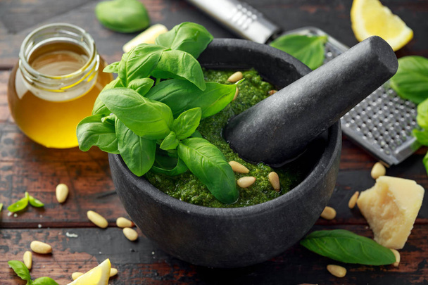 Zielone Pesto bazyliowym w marmurowy moździerz z parmezanem sera, orzeszków piniowych, czosnku i cytryny. - Zdjęcie, obraz