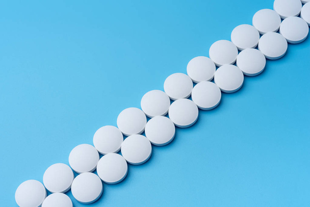 Pillole mediche bianche su sfondo blu diagonalmente. Laboratorio di prodotti farmaceutici
. - Foto, immagini