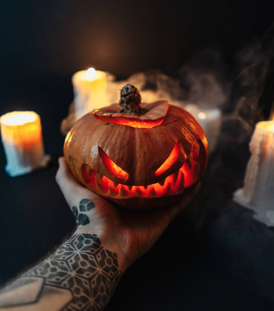 Man hand holding carved Halloween pumpkin on dark background. - Fotoğraf, Görsel