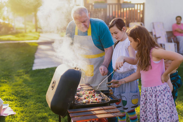 happy family cooking at grill outdoor - Photo, Image