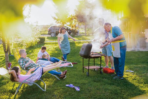 familia feliz teniendo un picnic en el patio trasero en un hermoso día de verano
 - Foto, Imagen