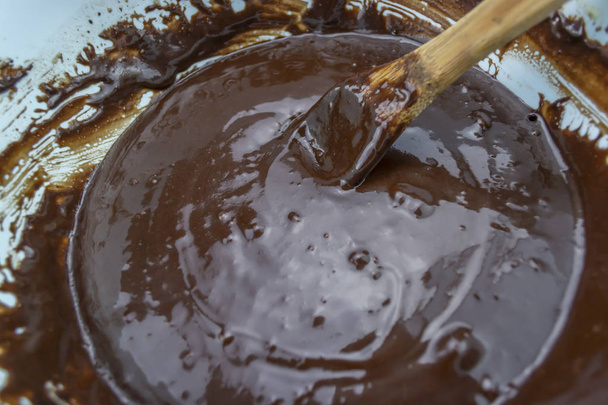 Blick auf Behälter voller Schokolade mit Holzlöffel, frisch verrührt zum Konfekt - Foto, Bild