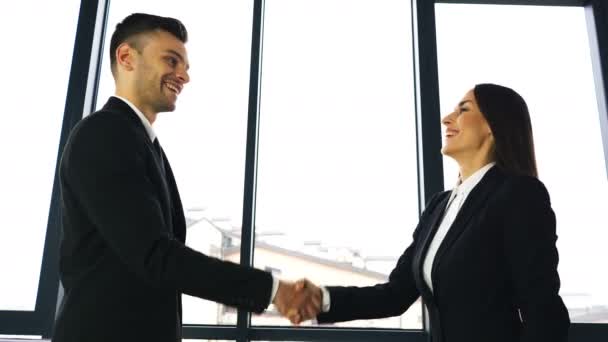 4k. Twee zakenpartner, man en vrouw, met plezier handen schudden wanneer office vergadering.  - Video