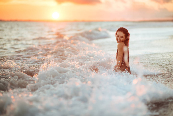 Silhouette eines Mädchens im Wasser bei Sonnenuntergang. Sommerzeit. - Foto, Bild