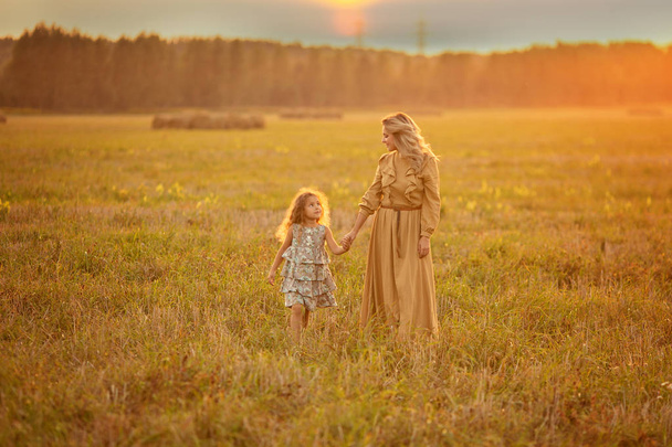 Mother and daughter walking on field during sunset - Zdjęcie, obraz