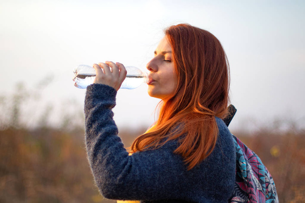 Young redhead girl drinks water  - Photo, Image