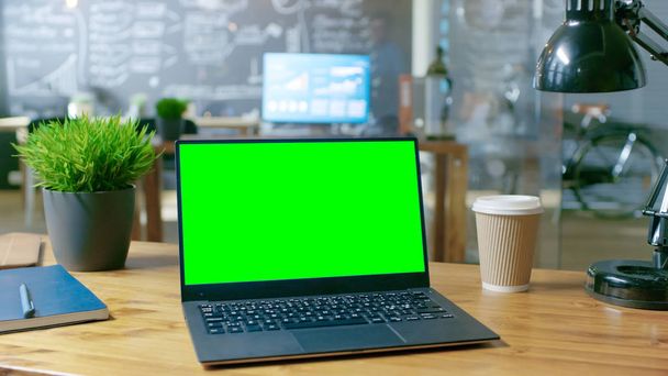 オフィスの机の上にモックアップ緑色の画面モニターとパソコンが立っています。昼背景スタイリッシュなクリエイティブ ・ オフィスの. - 写真・画像