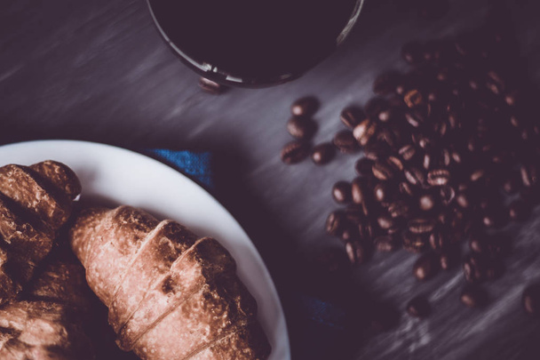 Macro shot of fresh croissants and coffee on a black background. Dessert and coffee beans. Mate moody color. concept of breakfast. Top view. - Zdjęcie, obraz
