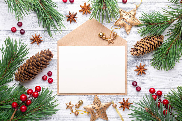 Fir branches, gifts and an envelope on a light wooden background. Cranberries, spices, holly berries. Christmas background. Flat lay, top view, copy space. - Foto, Bild