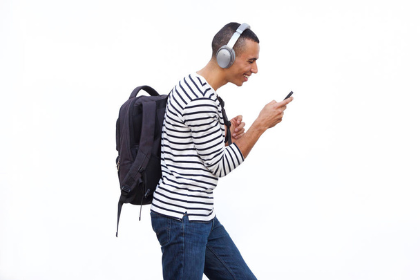 Profile portrait of young man walking with mobile phone and listening to music with headphones - Valokuva, kuva