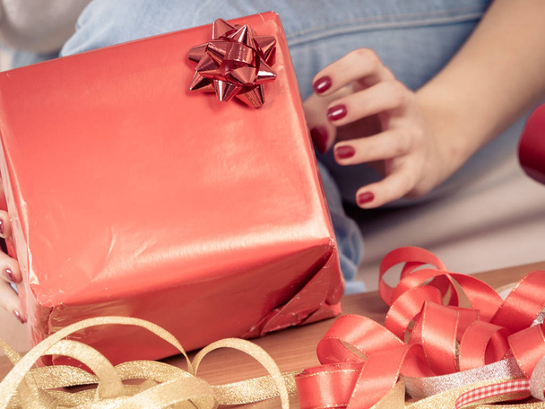 Holiday gifts, seasonal concept. Woman in sitting on sofa preparing and packing christmas presents - Valokuva, kuva