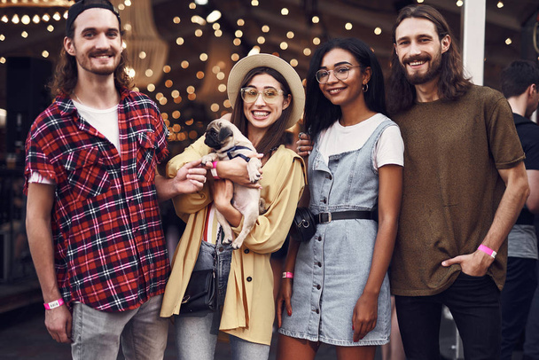 Four friends smiling and posing for photo with cute puppy - Foto, imagen