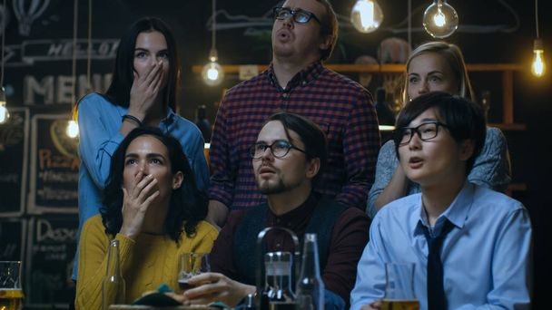 Young People in the Bar Watch TV Suddenly Breaking News Show that Tragic Events Unfold. Young People Are Horrified, Saddened and Shocked. - Φωτογραφία, εικόνα