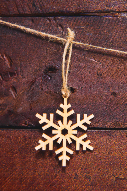 Kerst sneeuwvlokken op een houten achtergrond. Eco-vriendelijke speelgoed voor het verfraaien van de kerstboom. Houtproducten voor decoratie. Kerstdecoraties gemaakt van multiplex - Foto, afbeelding