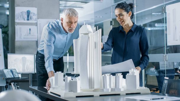 建築局の 2 つのプロのエンジニアは、都市地区のモデルで作業します。機能的な建物モデルに都市プランナー仕事. - 写真・画像