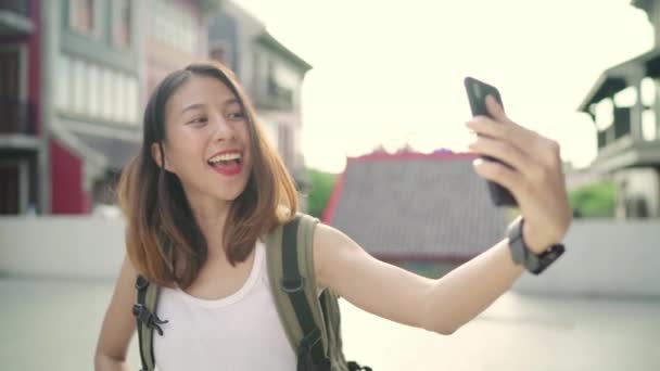 Alegre bela jovem asiático mochileiro blogger mulher usando smartphone tirar selfie enquanto viaja em Chinatown, em Pequim, China. Estilo de vida mochila turista viagem férias conceito
. - Filmagem, Vídeo