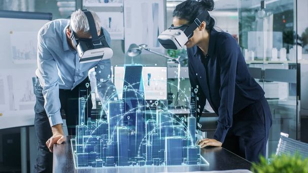 Male and Female Architects Wearing  Augmented Reality Headsets Work with 3D City Model. High Tech Office Professional People Use Virtual Reality Modeling Software Application. - Fotografie, Obrázek