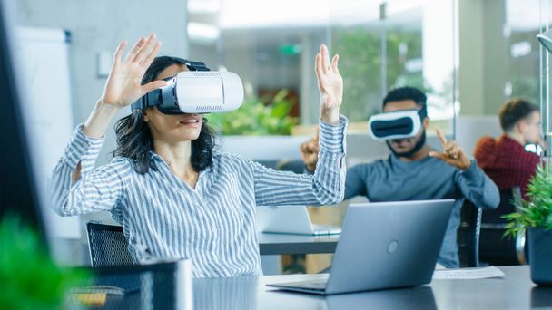 Female Virtual Reality Engineer/ Developer Wearing Virtual Reality Headset Creates Content With Her Colleagues. Bright Young People Work on the Augmented & Mixed Reality Project. - Photo, Image