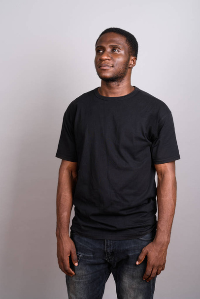 Νεαρή Αφρικανή άνθρωπος φορώντας μαύρο πουκάμισο γκρι φόντο - Φωτογραφία, εικόνα