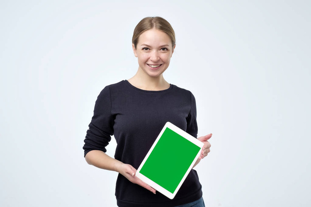 緑色の画面を示すデジタル タブレットを使用して黒い服を着た白人女性. - 写真・画像