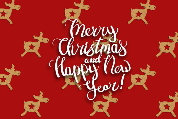 Houten Christmas speelgoed herten is bekleed met een patroon op een rode geïsoleerde achtergrond. Toegevoegde tekst vrolijk kerstfeest en gelukkig Nieuwjaar. Minimalistische stijl. Plat lag, top uitzicht. - Foto, afbeelding