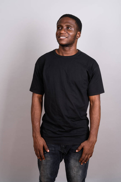 Nuori afrikkalainen mies yllään musta paita vastaan harmaa tausta
 - Valokuva, kuva