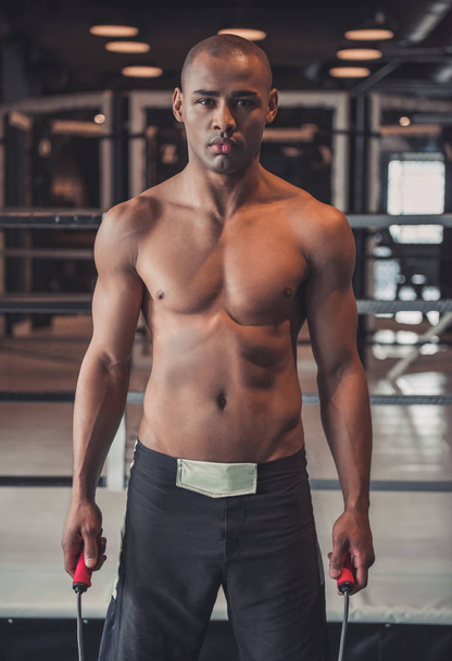 Boxeador afroamericano sostiene una cuerda y mira a la cámara mientras entrena en el gimnasio
 - Foto, imagen