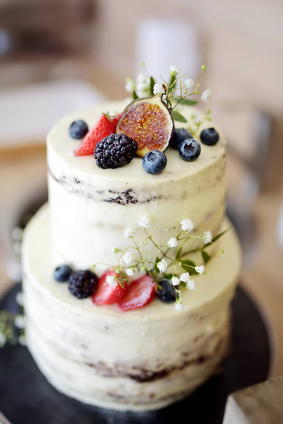 Delicious chocolate wedding cake decorated with various fruits and berries - Foto, Bild