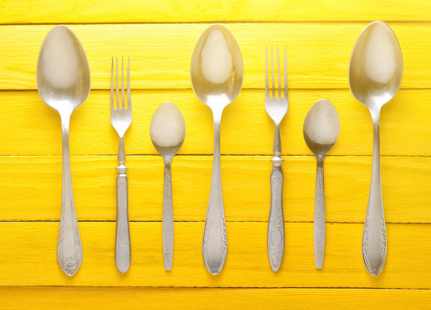 A set of spoons and forks on a yellow wooden table. Top view. - Photo, Image