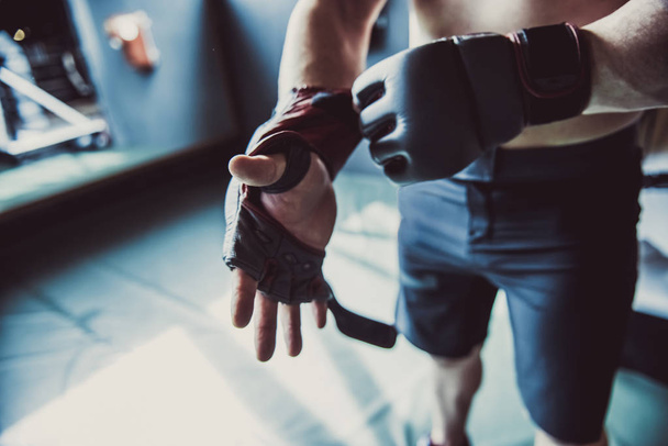 Spor salonunda tren hazırlarken boks eldivenleri koyarak boksör kırpılmış görüntü - Fotoğraf, Görsel