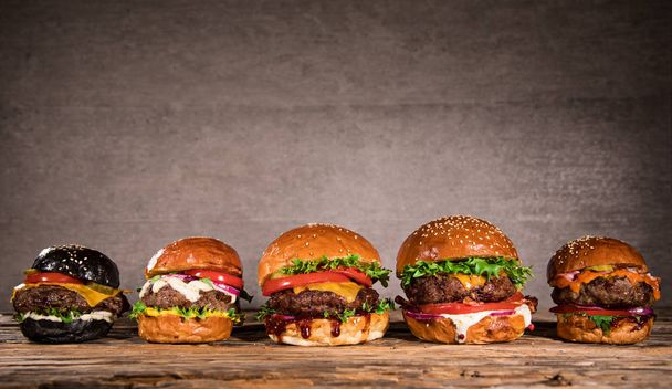 Close-up of home made tasty burgers on wooden table. - Photo, image