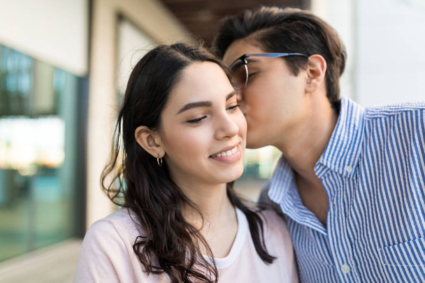 Closeup of male partner kissing on cheek of pretty woman in shopping mall - Fotografie, Obrázek