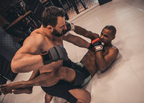 Két férfi a boksz-kesztyűket és rövidnadrág harcolnak a ketrec - Fotó, kép