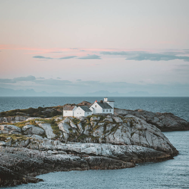 Sunrise and Sunset at Henningsvaer lighthouse with pink sky. The small fishing village located on several small islands in the Lofoten archipelago, Norway over a blue sky with clouds. - Φωτογραφία, εικόνα