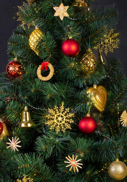 Gold, red and straw vintage decorations in the Scandinavian style on an artificial Christmas tree, close-up - Photo, Image
