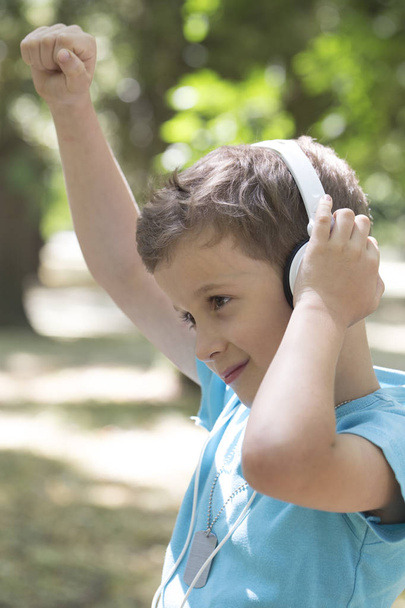 petit garçon mignon d'âge préscolaire écoute de la musique et montre de la satisfaction. Il leva la main haut et profiter de son groupe préféré
 - Photo, image