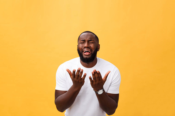 Studioporträt eines jungen afrikanisch-amerikanischen Mannes in weißem Hemd, die Hände im Gebet haltend, mit nachdenklichem skeptischem Gesichtsausdruck in die Kamera blickend, etwas ahnend. Körpersprache. - Foto, Bild